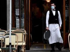 Aide aux restaurants et commerces après le Covid: éligibilité Un serveur portant un masque devant l’entrée d’un restaurant vide