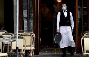 Aide aux restaurants et commerces après le Covid: éligibilité Un serveur portant un masque devant l’entrée d’un restaurant vide