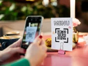 QR code de menu restaurant : pour un menu sans contact une femme scanne le qr code d'un menu dans un restaurant par le caméra d'un smartphone